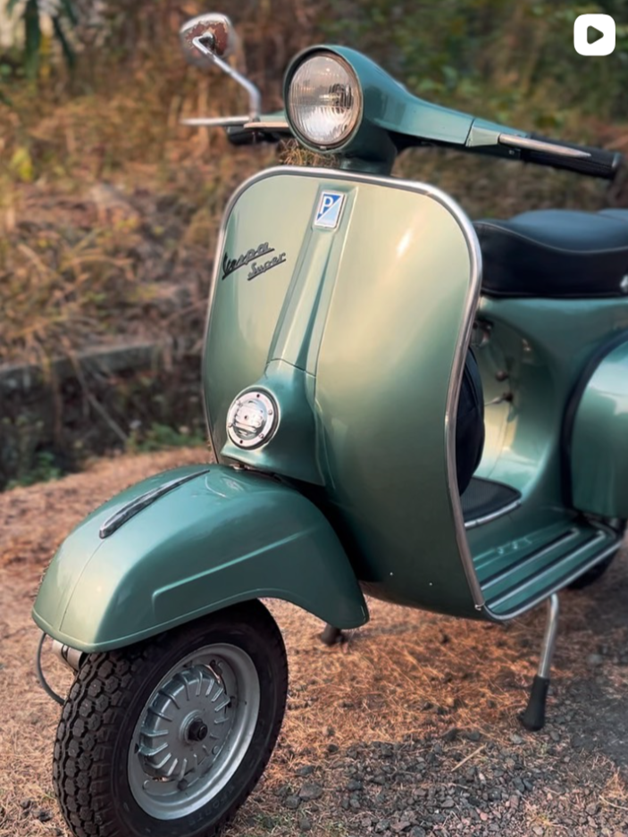 Vespa hijau sage dengan lampu bulat dan detail krom